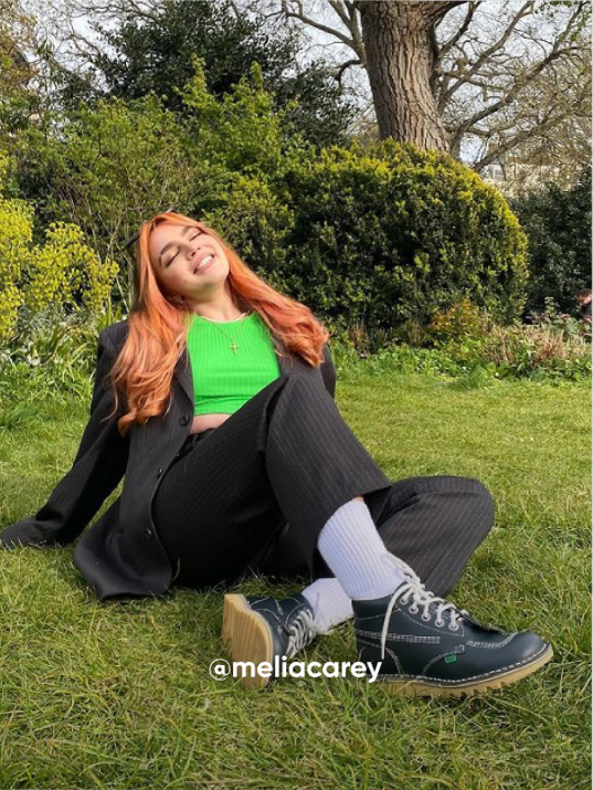 woman smiling outside while sitting on the grass - Visit Kickers Instagram