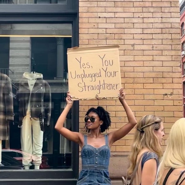 A photo of a girl holding a sign saying yes you unplugged your straightener. visit our instagram