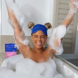 Woman sat in bathtub covered in bubbles using In Your Dreams Sleep Scrub & Soak. Shop All Product.