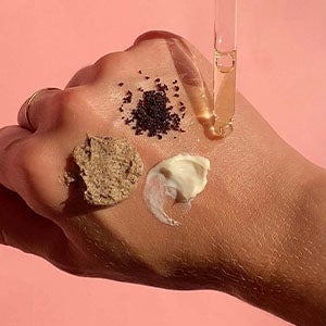 Scrub, Moisturizer and Coffee on top of the hand with Booty drops. Shop All Products