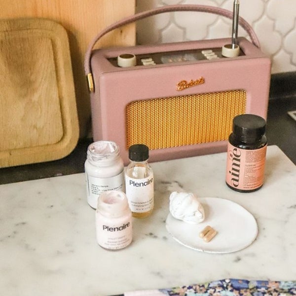 Plenaire Violet Paste Blemish solution on a marble table with a vintage pink radio. Visit our instagram