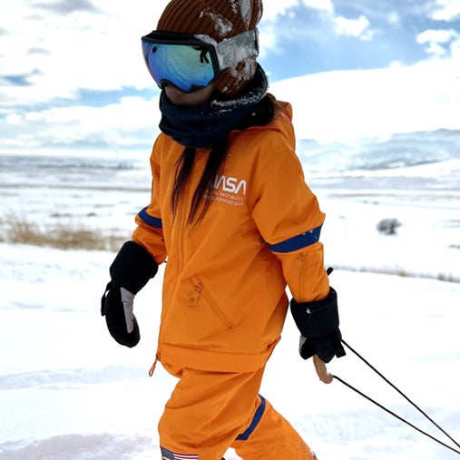 A kid wearing an orange nasa snowsuit.