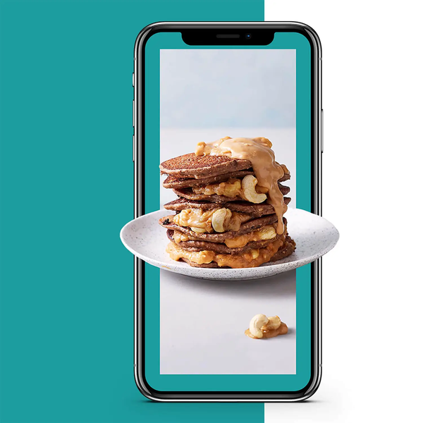 Graphic on a mobile phone of a plate of pancakes with peanut butter spread and topped with cashew nuts.