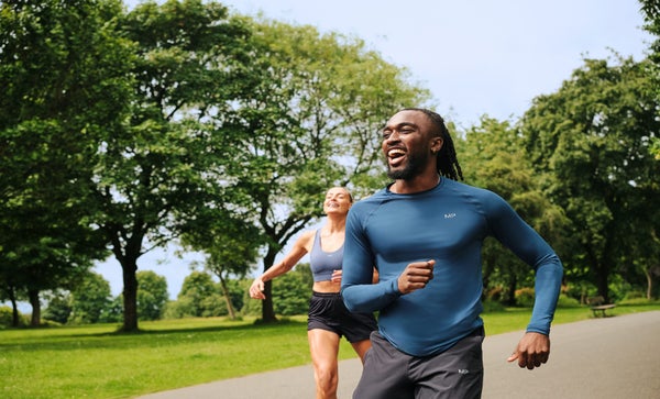 Un uomo e una donna che fanno jogging in abiti MP in un parco pubblico sorridenti.