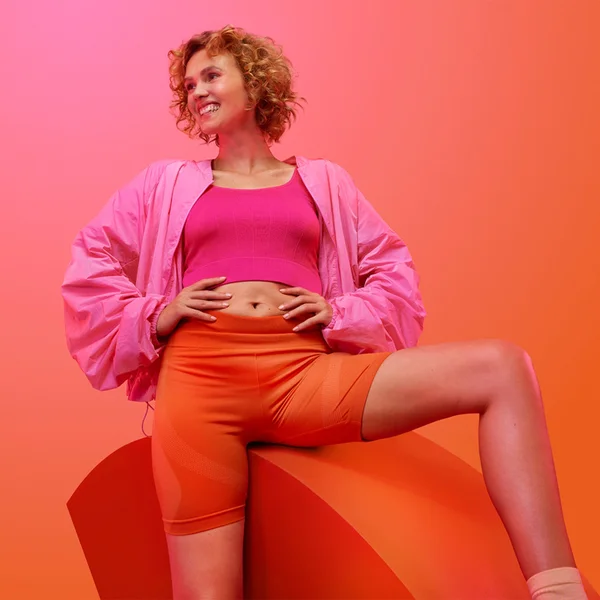 Blonde lady smiling with her hand on hips while looking to the side.