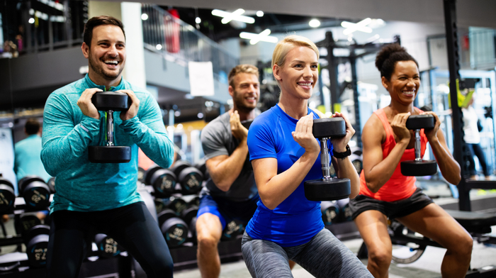 A group of people enjoying dumbbells' squat