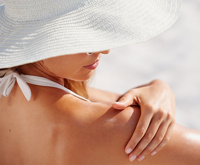 Woman-with-white-hat-applying-sunscreen-1 | Dermstore Blog