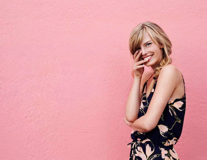 woman smiling against a pink wall