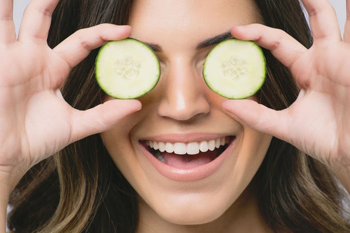 woman placing cucumbers over her eyes