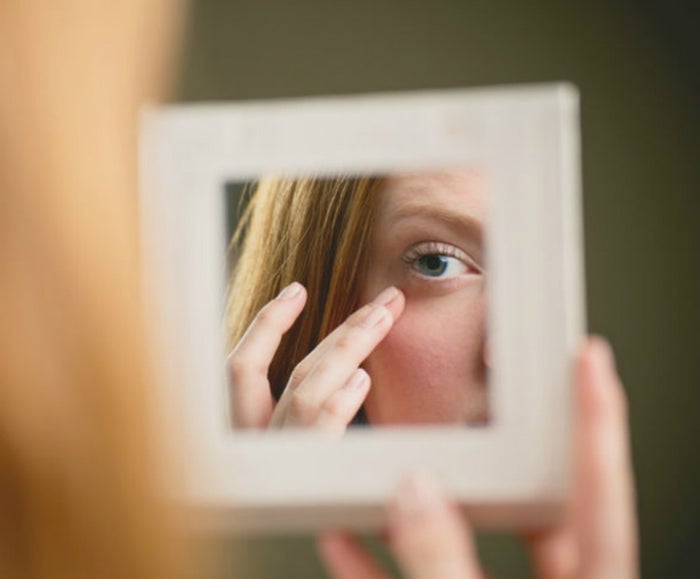Woman checking under-eye area in mirror