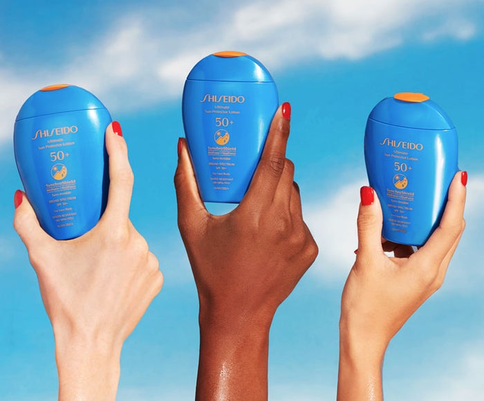 Hands holding Shiseido sunscreens