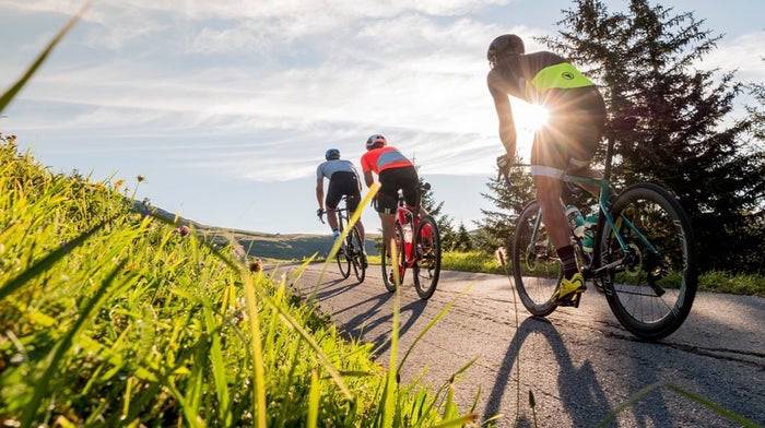 Three cyclists head into the sunset