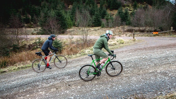 Duo of cyclists cycle along dirt road