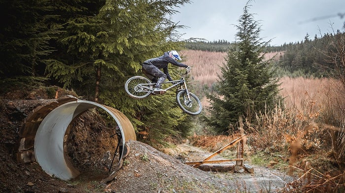 Endura rider mid jump between roads in grassy hills