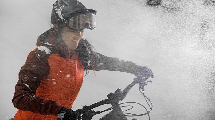 Lady is sprayed by snow in orange Endura jacket