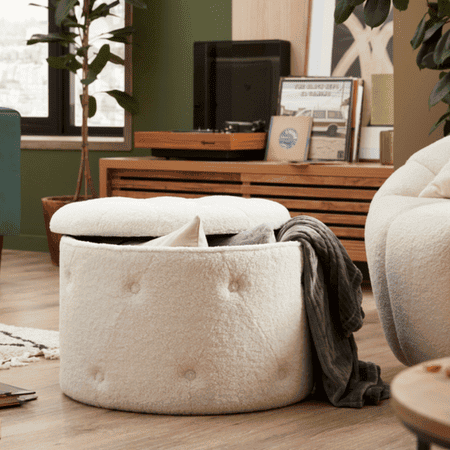 White fabric, round storage box with pillows and a throw hanging out.