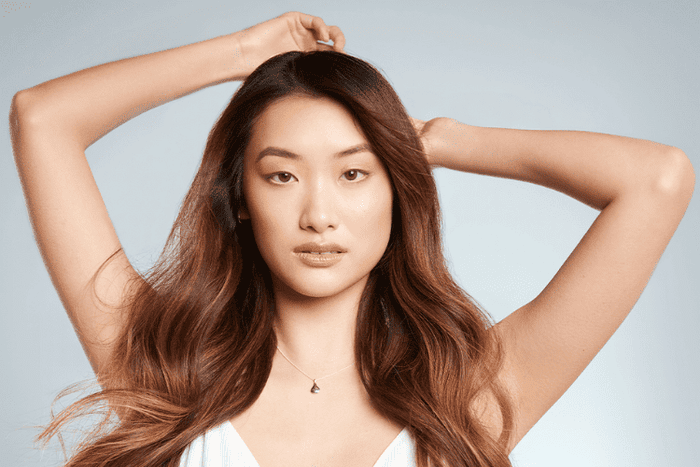 woman with brown hair holding arms above her head