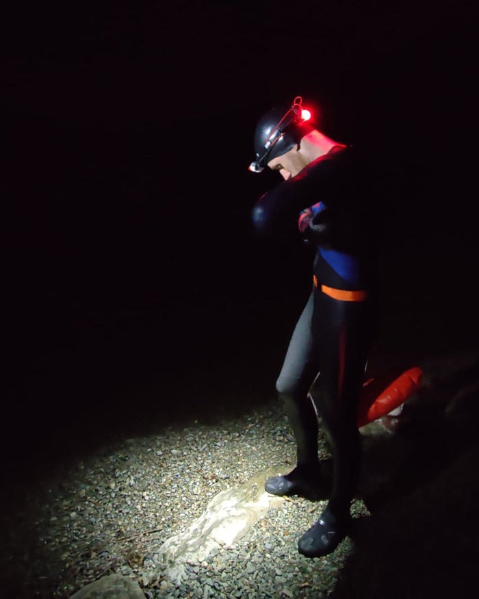 Man swims in lake in Speedo swimwear at night