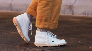 Someone wearing a white pair of Kickers classic boots and brown trousers.