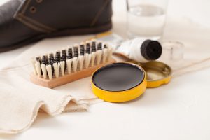 Shoe cleaning supplies including polish, a brush and a cloth.