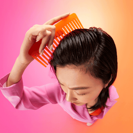 brown haired woman using an orange comb