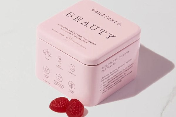 manifesto beauty tin with two strawberry shaped gummies out of the tin