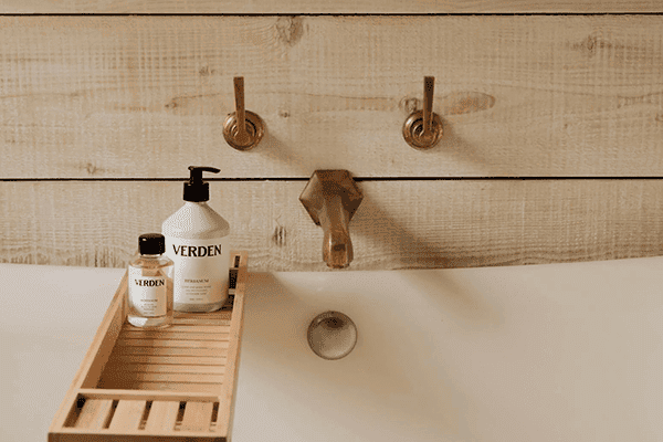 a bath tub, with VERDEN oil and body lotion bottles near the bath