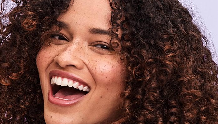 model smiling wide with curly hair and freckles