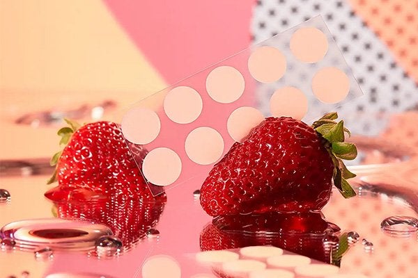 two strawberries with a row of peace out spot patches against a peach, pink and stripy background