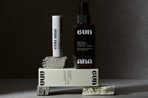 a collection of gun ana SPF products placed randomly on stones. shot against a black background in a studio