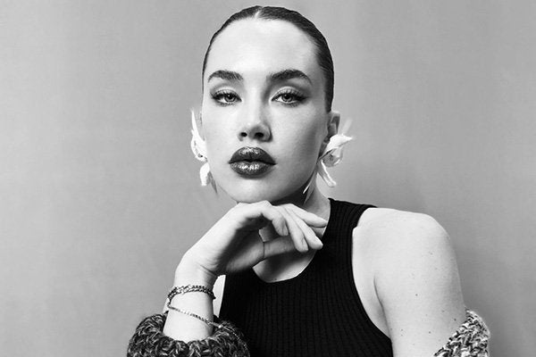 isamaya ffrench wearing large sculptural earrings looking at the camera and placing her left hand below her chin. photo is a headshot in black and white