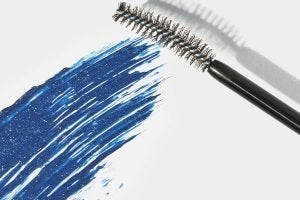 a mascara wand swatching a blue mascara. shot in a studio against a white background
