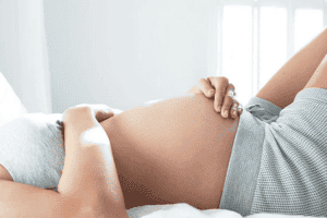 pregnant woman lying down holding bump