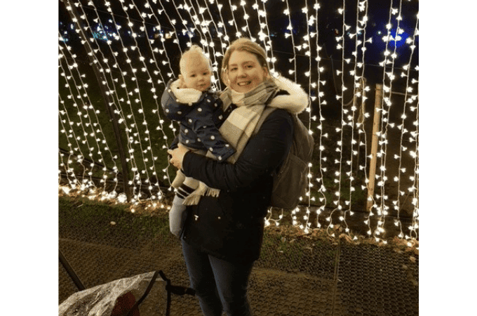 mum holding child in front of christmas lights