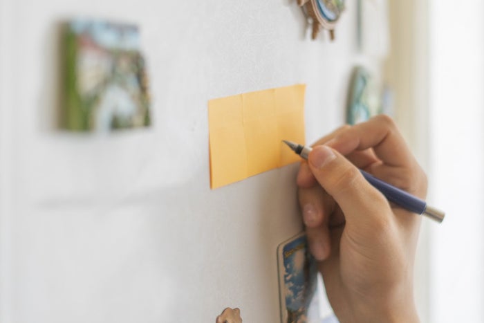 A person writing on a sticky note attached to the fringe.
