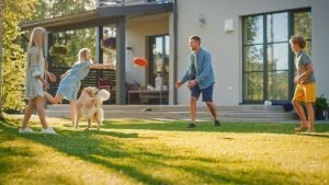 A family of four playing with a ball in their back garden. The dog is running around. 