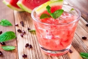 Watermelon and cranberry cooler standing on a wooden table. 