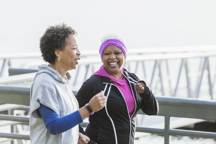 Two middle aged women smiling and talking on a run. 