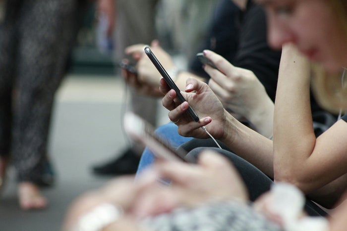 People sitting together, all using smartphones, focused on their screens.