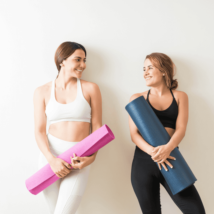 Two women holding yoga mats 