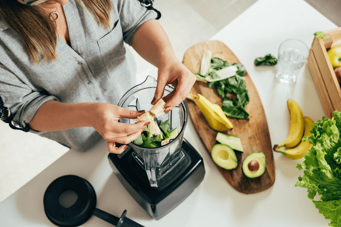 Woman making banana, lettuce and avocado smoothie