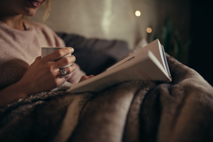 Woman is reading a book with a cup of tea before bed