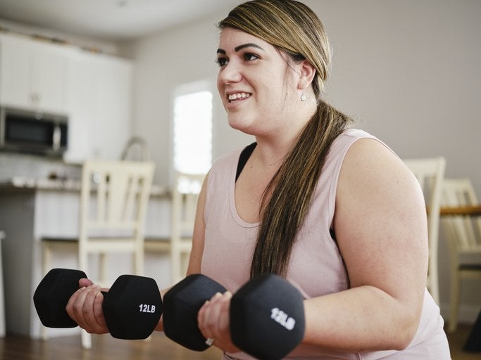 A woman exercising in her home with hand weights.