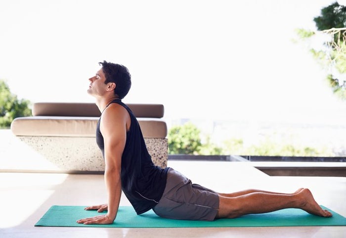 A side view shot of a content young man doing yoga at home