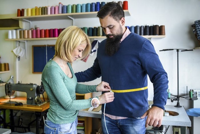 The dressmaker takes a measure of a male model in a tailor shop