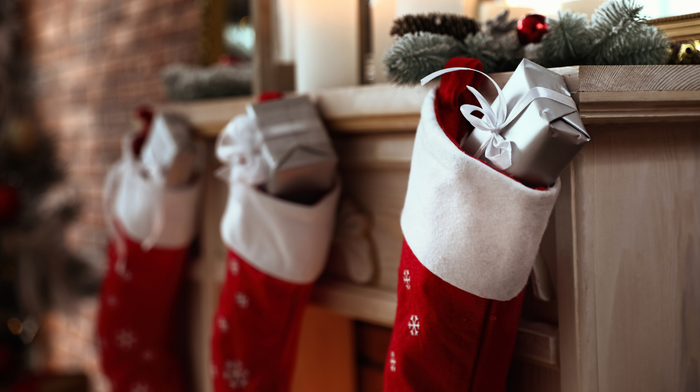 Christmas stockings hanging by the fireplace with skincare gifts inside.
