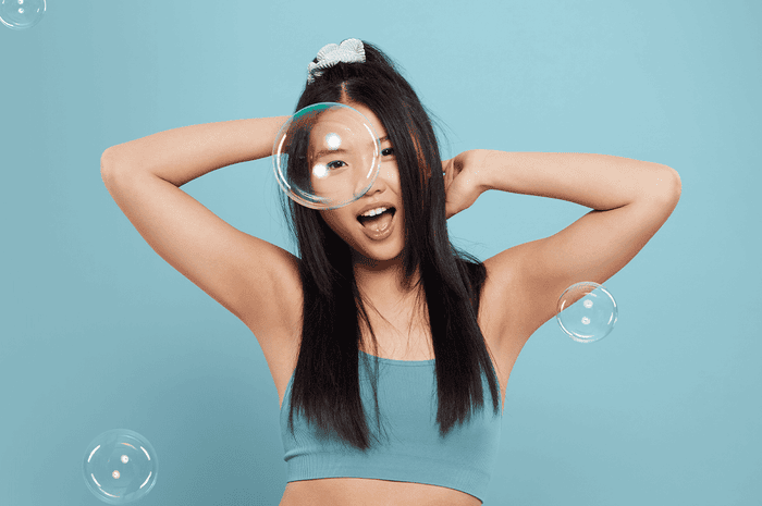 Woman with arms up dancing, with a blue background and bubbles