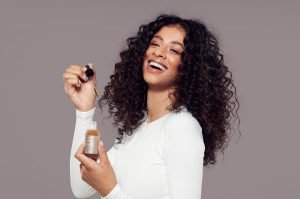 Woman with curly hair holding up the Grow Gorgeous Growth Serum