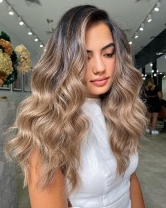 Woman with blonde highlights after blow-dry and curled in salon