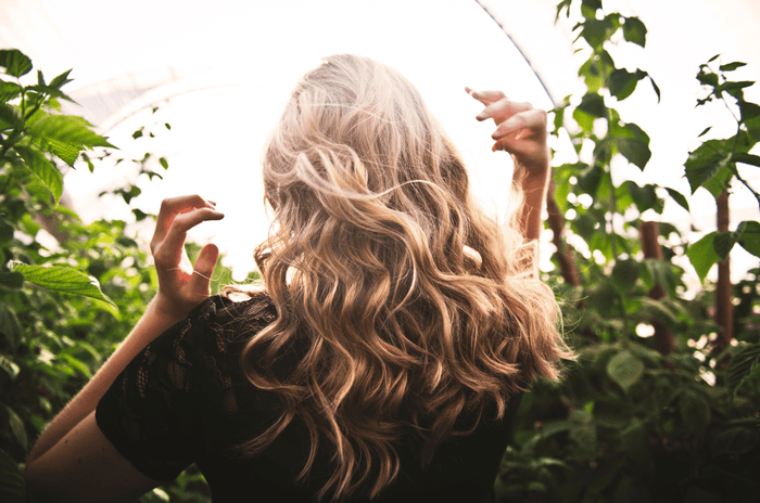 Woman with long brown hair with highlights showing results from using heatless curls